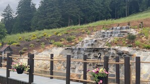 A stone waterfall, wooden deck, and hanging flower planters.