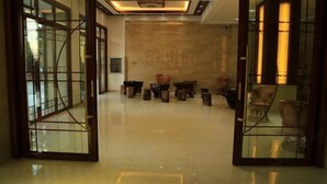 A spacious lobby with a polished floor, a central seating area with chairs, and a large wooden door with glass panels. - Mangshi Cuidi Hotel (Mangshi)