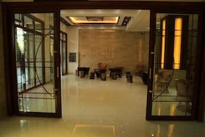 A lobby with a glass partition, a reception desk, and a seating area with chairs. - Mangshi Cuidi Hotel (Mangshi)