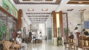 A hotel lobby with a reception desk, seating area, and a decorative wall. - Mangshi Cuidi Hotel (Mangshi)
