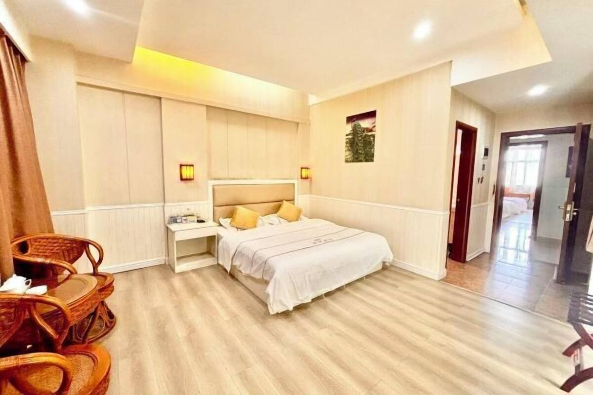A hotel room with a bed, bedside table, and a chair.