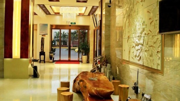 A hotel lobby with a wooden sculpture centerpiece, a reception desk, and a large TV screen on the wall. - Mangshi Cuidi Hotel (Mangshi)
