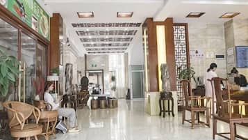 A hotel lobby with seating areas, a reception desk, and a decorative ceiling.