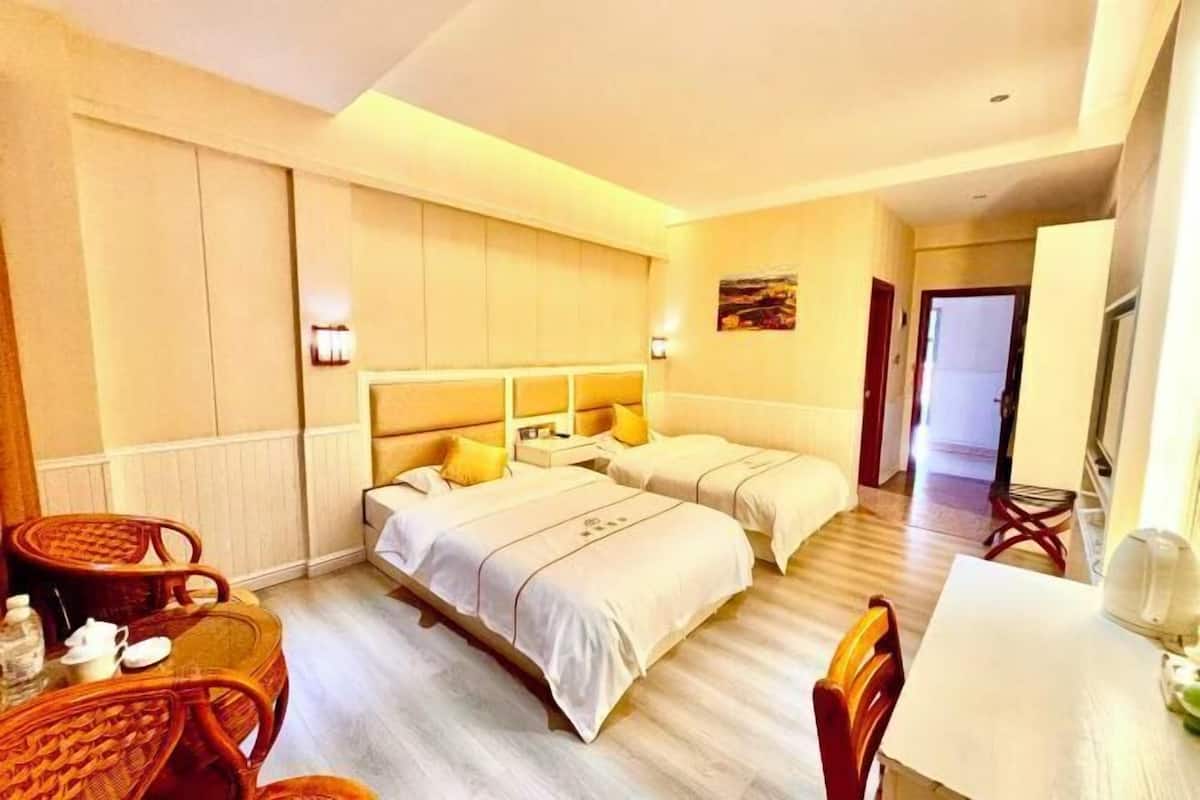 A hotel room with two beds, a dining table, and a sitting area with chairs.