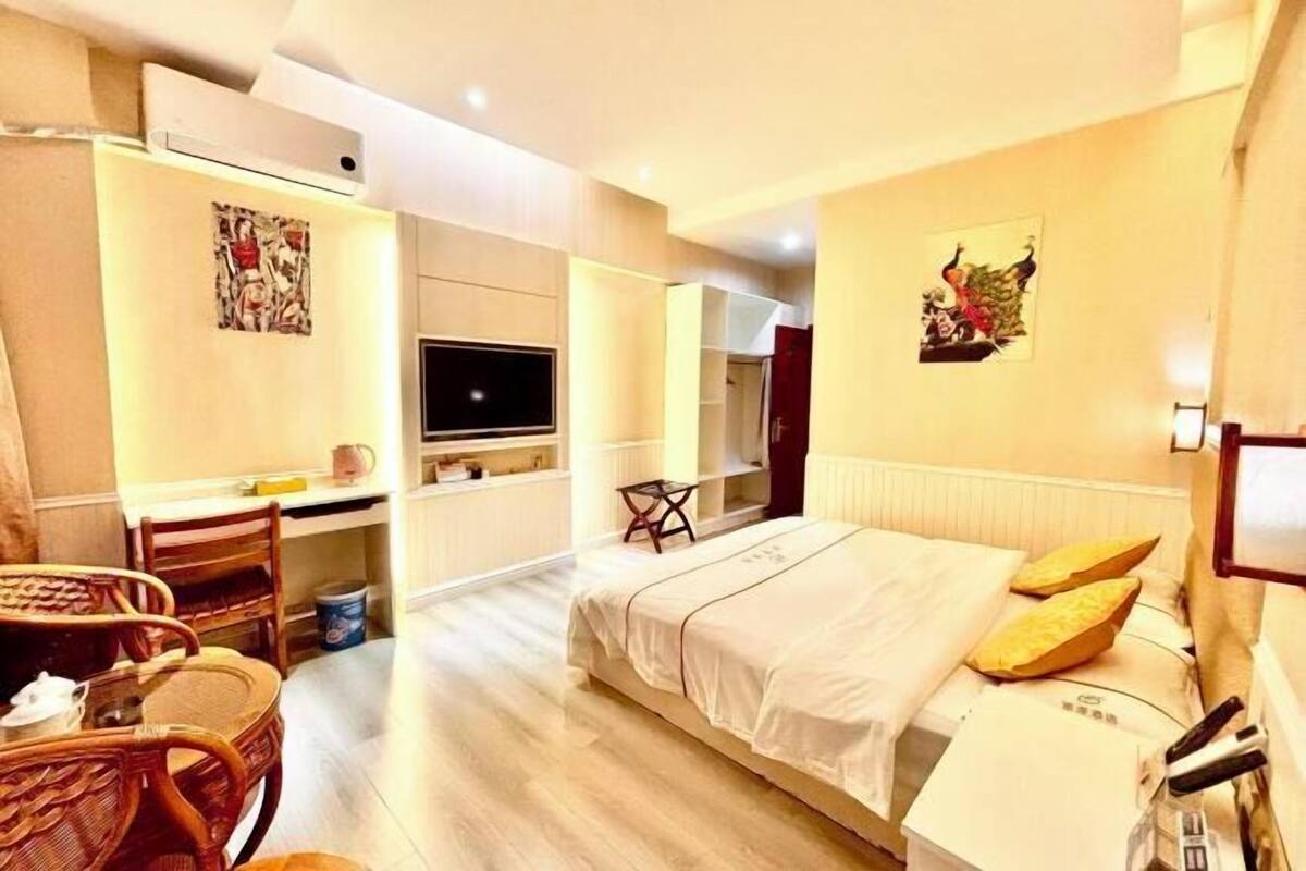 A hotel room with a bed, a desk, a chair, a television, and a radiator.