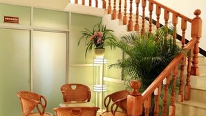 A staircase with wooden balusters, a wicker table with chairs, and a potted plant. - Mangshi Cuidi Hotel (Mangshi)