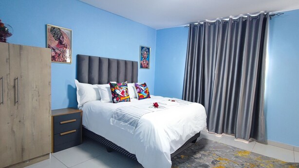 Een slaapkamer met een bed, een kledingkast en een gordijn.