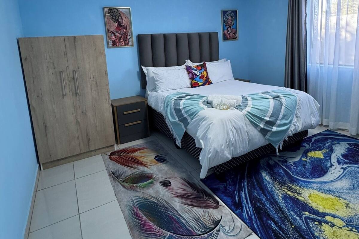 Une chambre à coucher avec un lit, des tables de chevet, une armoire et une fenêtre avec des rideaux.