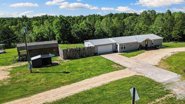 Einbungalow mit Garage, einem eingezäunten Garten und einem Schotterweg.