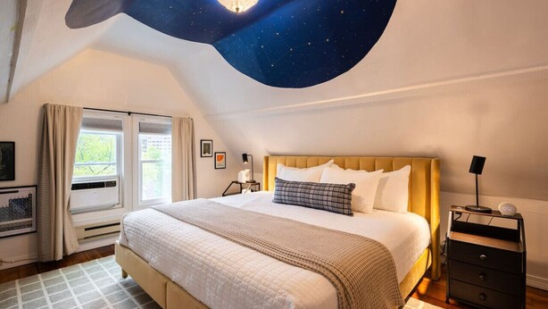 Ein Schlafzimmer mit einem Bett, einem Nachttisch und einer Decke mit Sternenmuster.