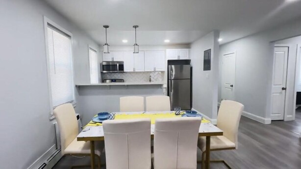 A compact kitchen with white cabinets, a microwave, a refrigerator, and pendant lights.