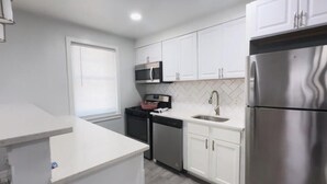A modern kitchen with white cabinetry, stainless steel appliances, and a built-in oven.