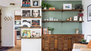 A living room with wooden cabinets, a white sofa, and a coffee table. There are books and decorative items on shelves.