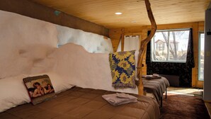 Une chambre confortable dans un chalet, avec un lit, une fenêtre et un plafond en bois.