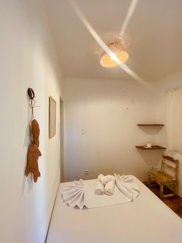 Ein Schlafzimmer mit einem Bett, einem Sessel, einer hängenden Fischskulptur und einem Regal mit einem Handtuch.