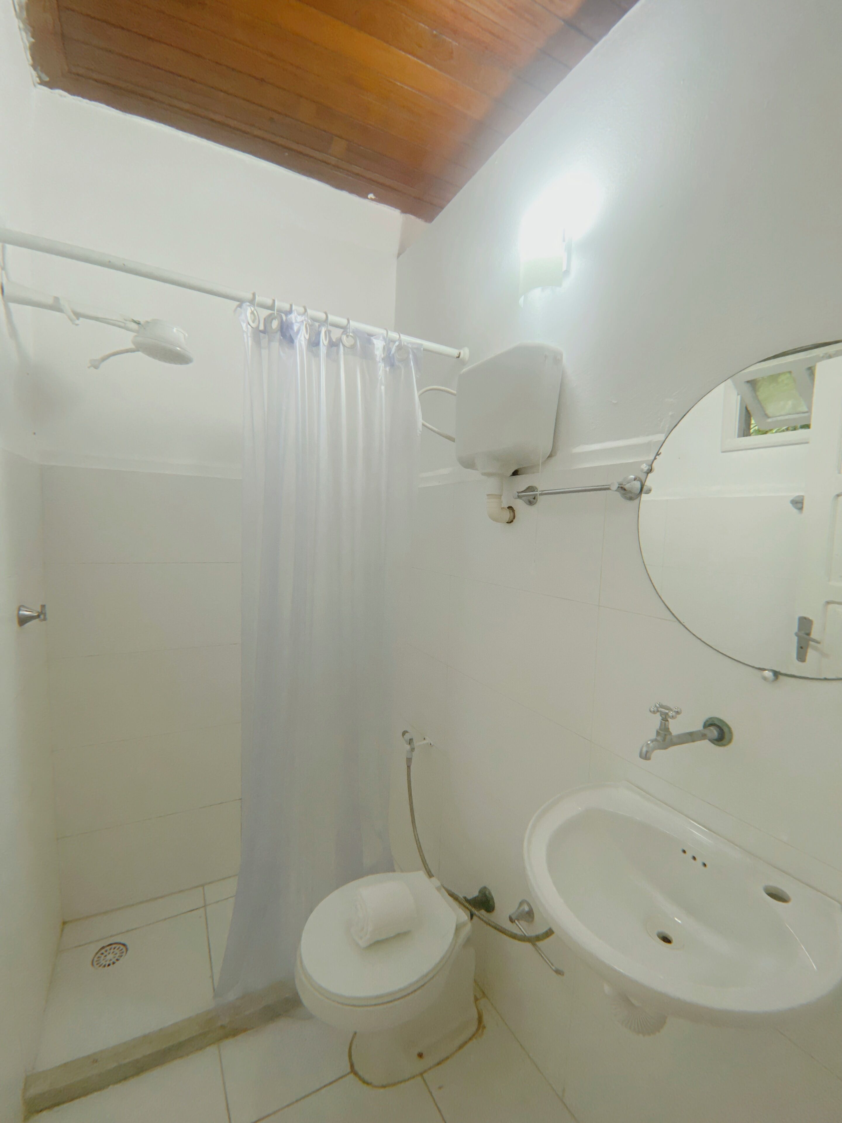 Un baño con ducha, inodoro, lavabo y espejo.