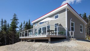 A two-story house with a balcony, large windows, and a red roof.