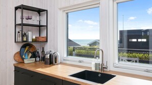 A modern kitchen with a wooden countertop, a black sink, and a shelf with kitchen items. - Amazing home in Juelsminde (Juelsminde)