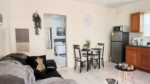 A compact living space with a kitchenette, a dining area, and a sofa with a pineapple pillow. - Crew Friendly Apartment apartment in walking distance to Simpsonbay Marinas (cole bay)