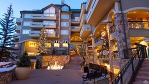 Een hotel met meerdere verdiepingen, een gevel van natuursteen, een kerstboom en een fontein in de binnenplaats.