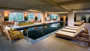 Une grande piscine intérieure dotée de chaises longues et d’un espace repas.