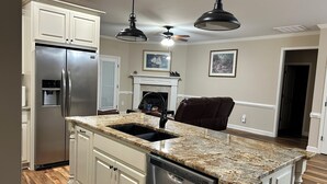 A kitchen with a stainless steel refrigerator, granite countertop, and a built-in dishwasher.