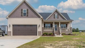 A two-story house with a garage, a front porch, and a well-maintained lawn.