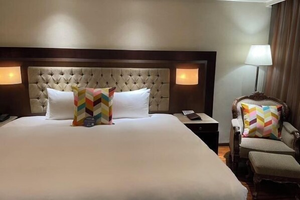 A hotel room with a large bed, two bedside lamps, a chair, and a nightstand. - Charming City Hotel (Taipei)