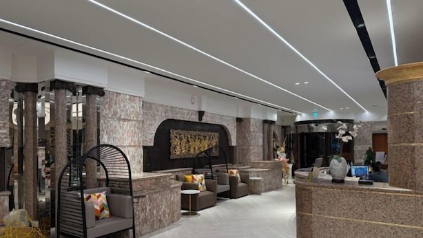 A modern lobby with a reception desk, seating area, and a decorative wall. - Charming City Hotel (Taipei)