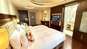 A hotel room with a large bed, a TV, a desk, and a bathroom visible through an open door. - Charming City Hotel (Taipei)