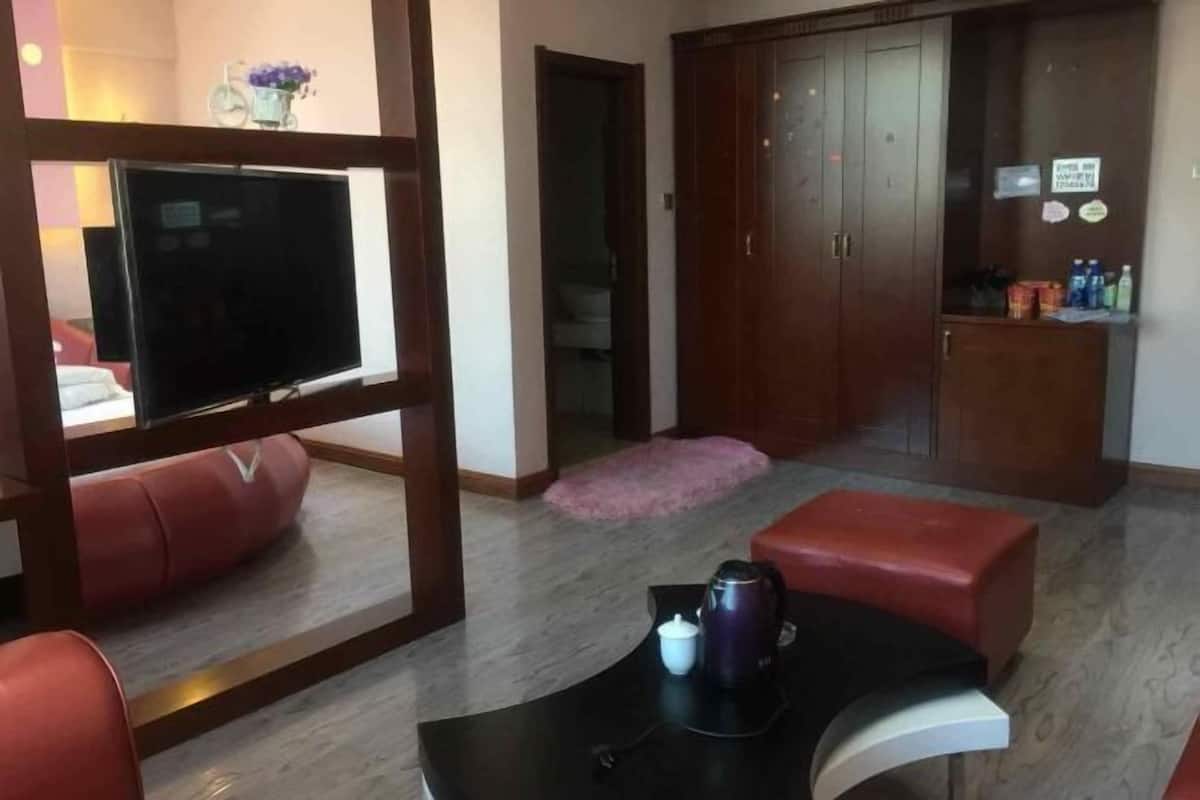 Un salon moderne avec un téléviseur, un canapé en cuir rouge, une table basse et une armoire en bois.