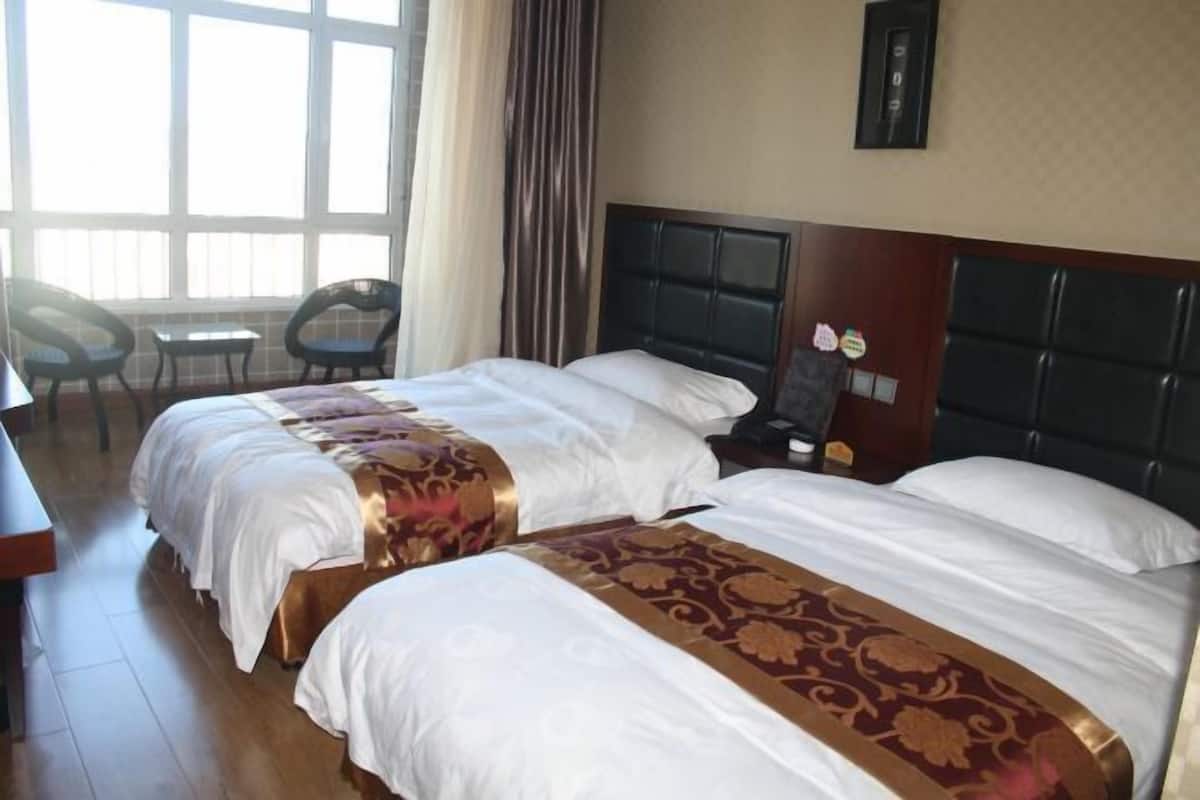 Une chambre d’hôtel avec deux lits, un bureau, des chaises et une grande fenêtre.