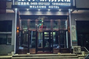 L’entrée d’un hôtel, avec une porte en verre, une enseigne au-dessus de la porte et un numéro de téléphone.