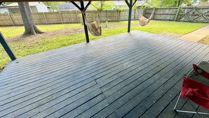 A covered wooden deck with a hammock and a red chair. - Charming 4-bedroom house with AC and WiFi in peaceful Texarkana (Texarkana)