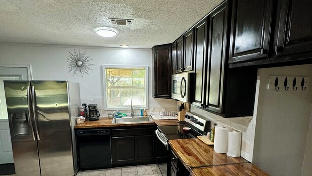 A modern kitchen with stainless steel appliances, dark wooden cabinets, and a granite countertop. - Charming 4-bedroom house with AC and WiFi in peaceful Texarkana (Texarkana)