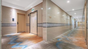 A hotel corridor with a wooden floor, beige walls, and a door with a sign. - Super 8 Hotel (Sanming Sanyuan Chengguan Furong Road) (Sanming)