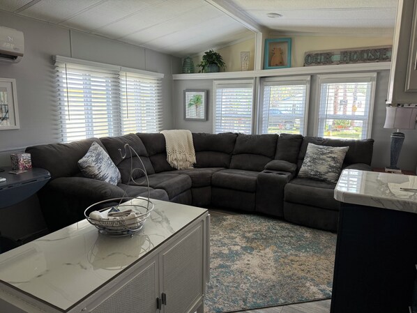 A modern living room with a sectional sofa, a marble coffee table, and a patterned rug.
