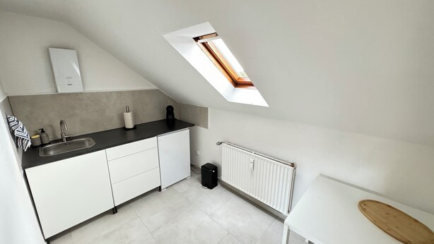 A modern kitchen with white cabinets, a black countertop, a skylight, and a white radiator. - City Apartment - Business, Uni, Handwerker - Free Wifi (Bochum)