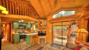 Interior de una cabaña de madera con cocina, comedor y sala de estar.
