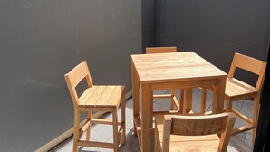 A wooden table and chairs set against a dark wall, with a tiled floor.