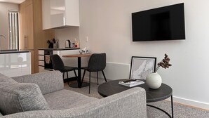 A modern living room with a grey sofa, a coffee table, and a TV mounted on the wall.