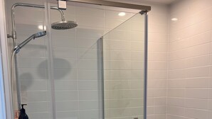 A modern bathroom with a glass-enclosed shower, a toilet, and a sink.