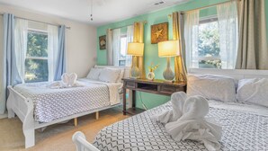 Une chambre avec deux lits, un bureau et un ventilateur de plafond.
