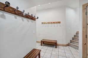 Un couloir avec un banc en bois, un porte-manteau avec des clubs de golf et un autre porte-manteau avec des crochets.