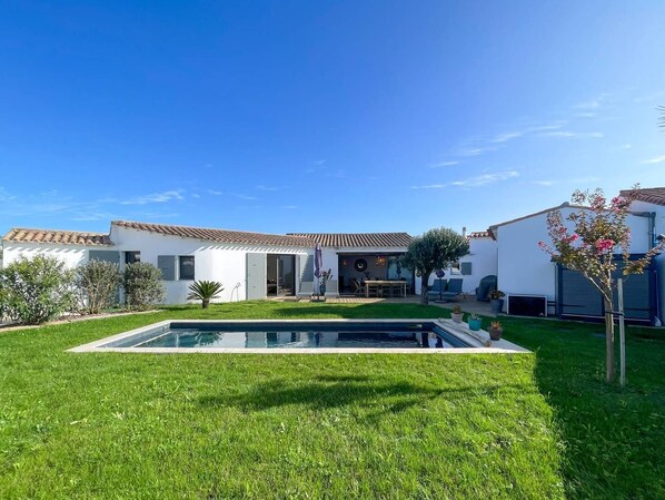 A modern house with a swimming pool, a patio, and a well-maintained garden.