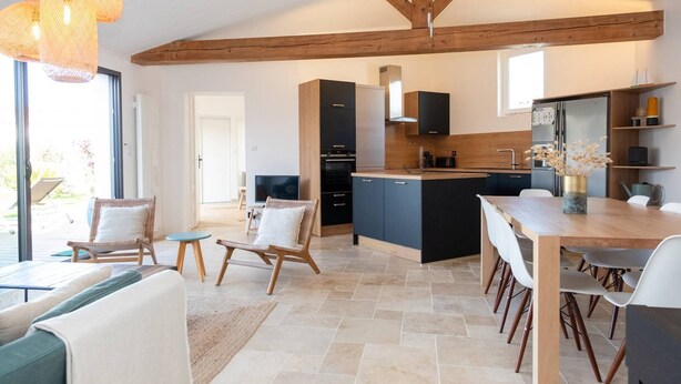 A modern kitchen with dark cabinets, a wooden ceiling, and a dining area with a table and chairs. - Alma - Renovated villa with heated pool few blocks from the beach (LE BOIS PLAGE EN RE)