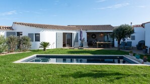 A modern house with a swimming pool, a patio with outdoor furniture, and a garden. - Alma - Renovated villa with heated pool few blocks from the beach (LE BOIS PLAGE EN RE)