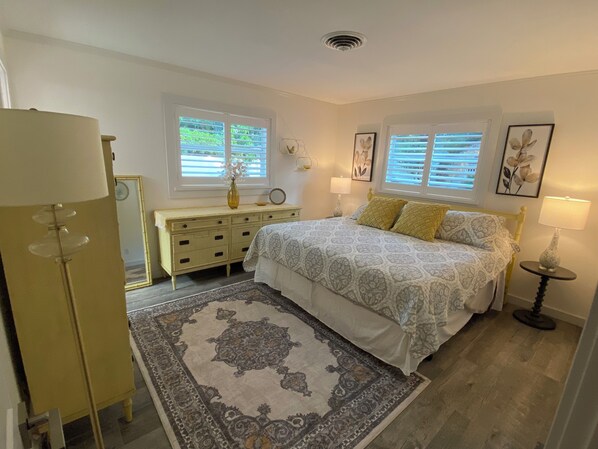 Un dormitorio con cama, mesitas de noche, cómoda y alfombra.
