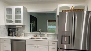 Una cocina moderna con gabinetes blancos, electrodomésticos de acero inoxidable y lavavajillas integrado.
