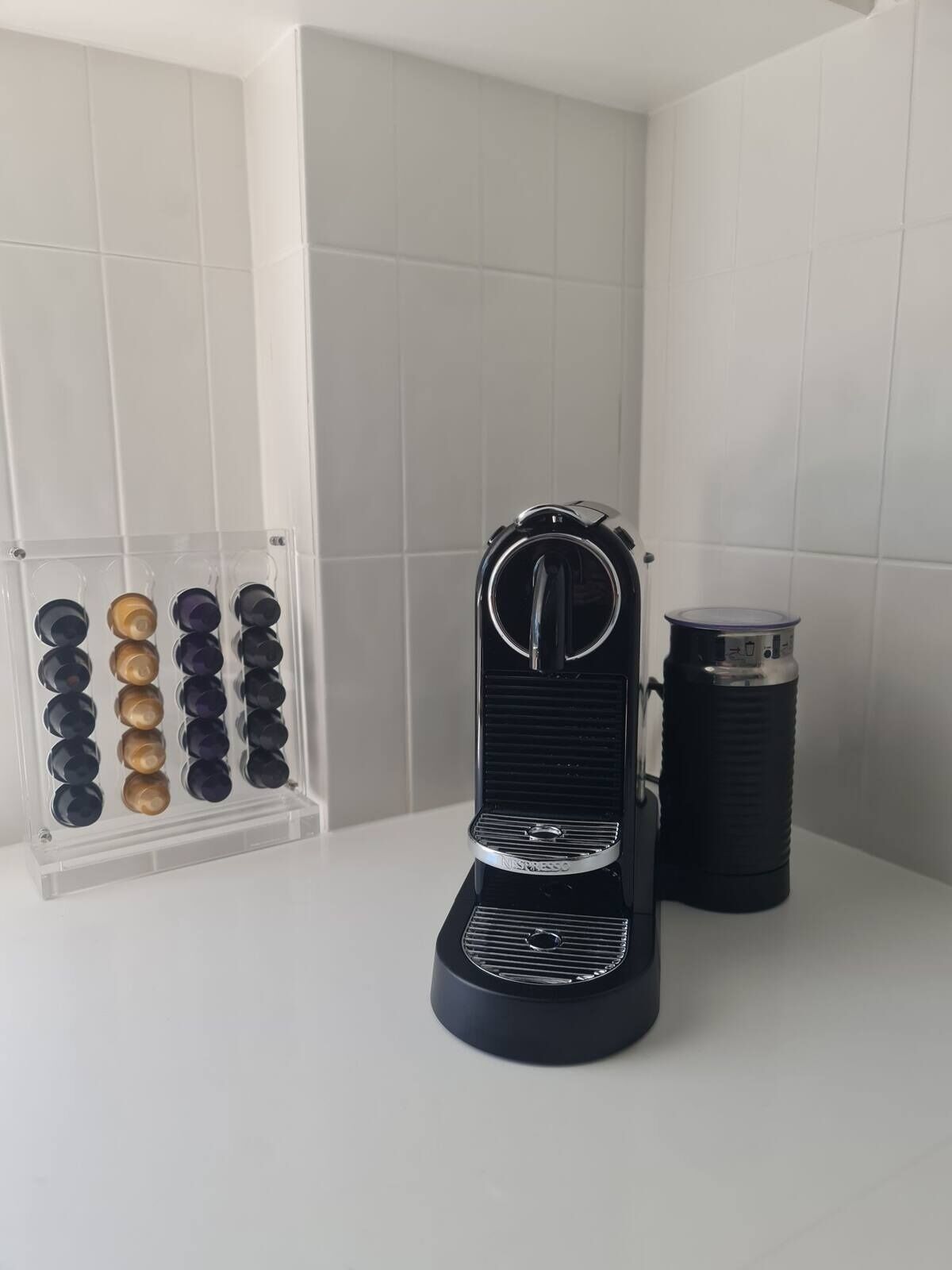 Een zwarte espresso machine met een koffiemolen op een wit aanrecht.
